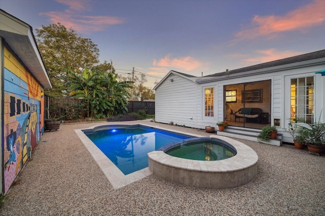 pool at dusk with an in ground hot tub