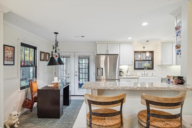 kitchen with decorative light fixtures, sink, white cabinets, and stainless steel fridge with ice dispenser