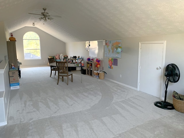 dining area featuring light carpet, ceiling fan, vaulted ceiling, and a textured ceiling