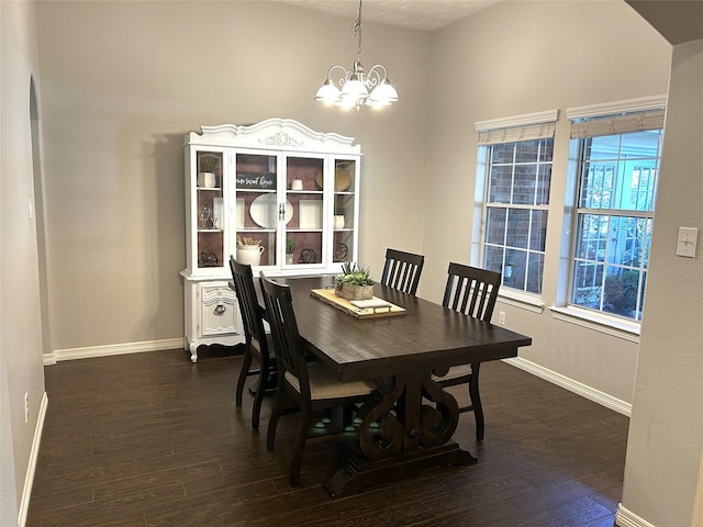 dining area featuring dark wood-type flooring and a notable chandelier