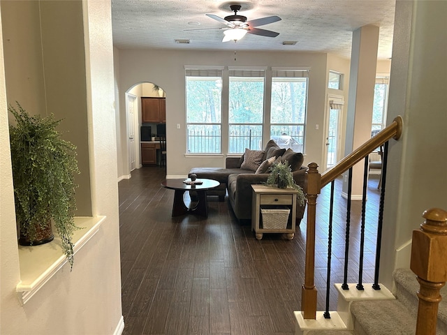 living room with dark hardwood / wood-style flooring, ceiling fan, and a textured ceiling