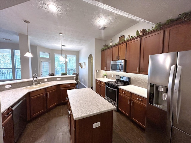 kitchen with sink, a center island, hanging light fixtures, dark hardwood / wood-style floors, and stainless steel appliances