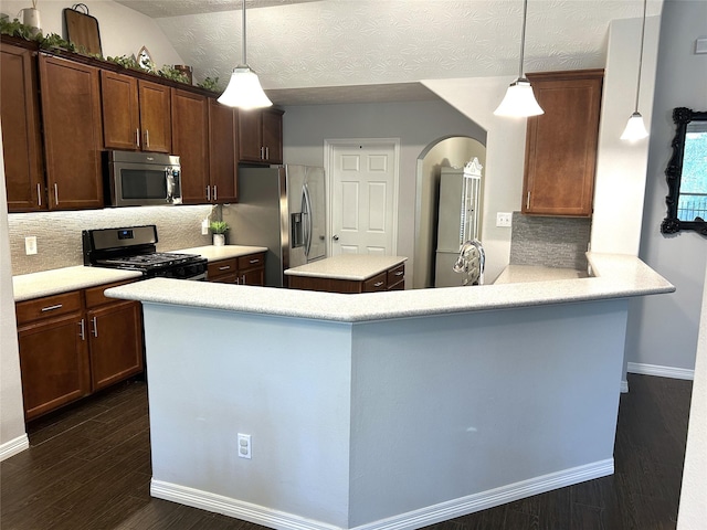 kitchen with dark hardwood / wood-style floors, hanging light fixtures, kitchen peninsula, stainless steel appliances, and dark brown cabinets