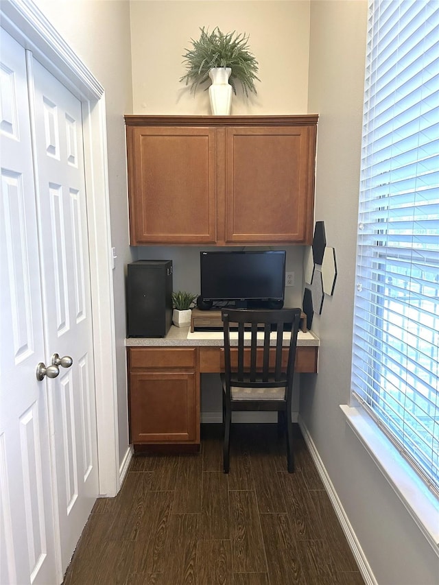 home office with built in desk and dark wood-type flooring