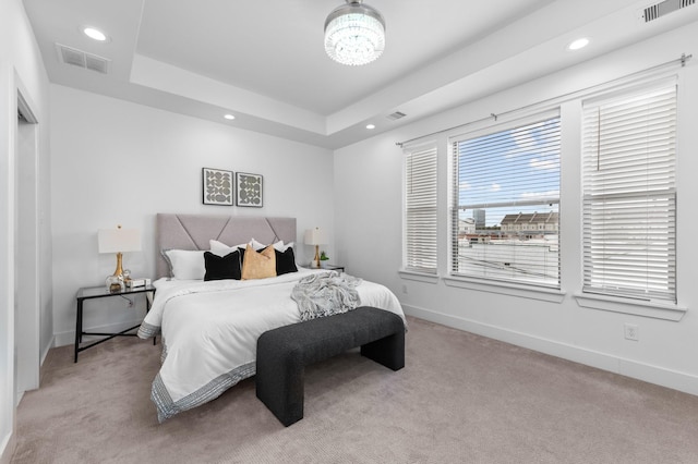 carpeted bedroom with a notable chandelier and a tray ceiling