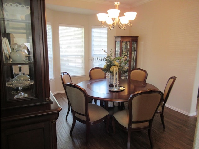 dining space with crown molding, dark wood-type flooring, and an inviting chandelier