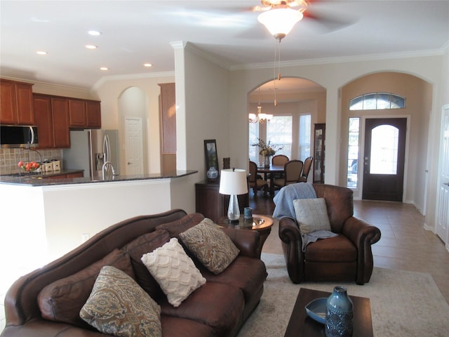 living room with an inviting chandelier, light tile patterned floors, and ornamental molding