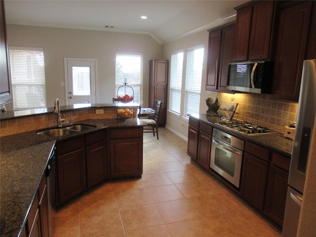 kitchen with sink, ornamental molding, stainless steel appliances, and dark stone counters