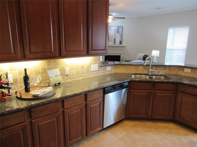 kitchen with sink, light tile patterned floors, stainless steel dishwasher, dark stone counters, and backsplash