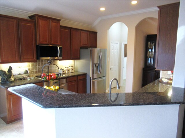 kitchen with ornamental molding, stainless steel appliances, kitchen peninsula, and backsplash