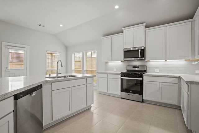 kitchen with stainless steel appliances, sink, white cabinets, and backsplash