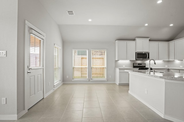 kitchen featuring white cabinetry, lofted ceiling, stainless steel appliances, and tasteful backsplash