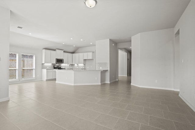 unfurnished living room with vaulted ceiling, sink, and light tile patterned floors