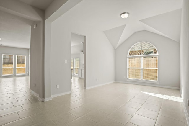 spare room featuring lofted ceiling, light tile patterned floors, and a wealth of natural light