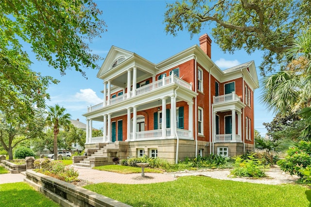 1428 Ball, Galveston, TX 77550 - view of front facade with a balcony, a chimney, a porch, a front yard, and brick siding