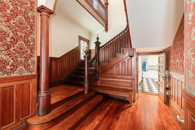 1428 Ball, Galveston, TX 77550 - stairway with wallpapered walls, a wainscoted wall, wood-type flooring, decorative columns, and a high ceiling