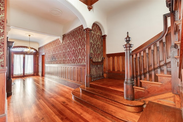 1428 Ball, Galveston, TX 77550 - staircase with a wainscoted wall, hardwood / wood-style flooring, a chandelier, arched walkways, and wallpapered walls