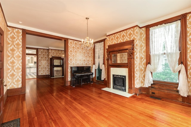 1428 Ball, Galveston, TX 77550 - unfurnished living room with wallpapered walls, a fireplace with flush hearth, hardwood / wood-style floors, a chandelier, and baseboards