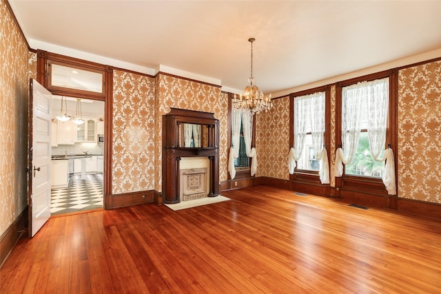 1428 Ball, Galveston, TX 77550 - unfurnished living room featuring hardwood / wood-style flooring, wallpapered walls, a chandelier, and baseboards