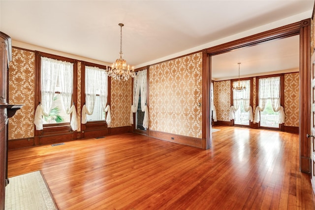 1428 Ball, Galveston, TX 77550 - unfurnished room with a chandelier, wallpapered walls, wood-type flooring, and baseboards