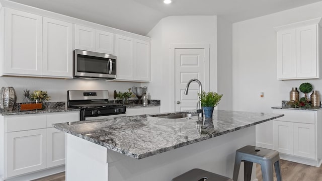 kitchen with white cabinetry, stainless steel appliances, a kitchen island with sink, and sink