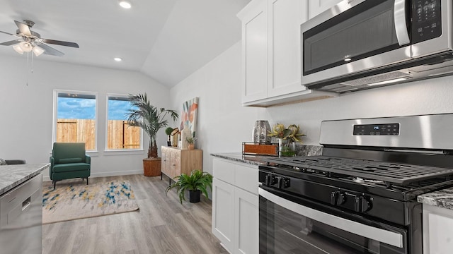 kitchen with stone counters, appliances with stainless steel finishes, white cabinets, and light hardwood / wood-style floors