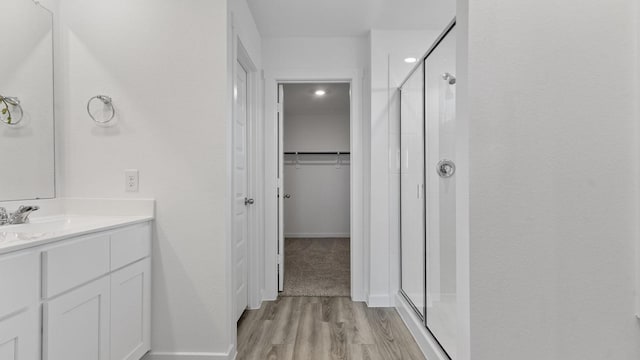 bathroom with wood-type flooring, an enclosed shower, and vanity