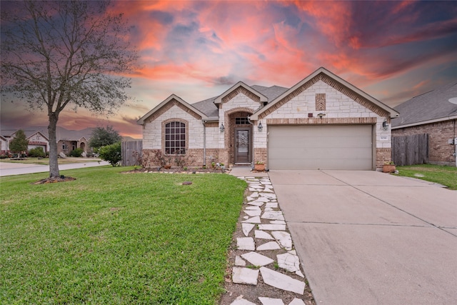 french country home with a garage, brick siding, driveway, and a yard