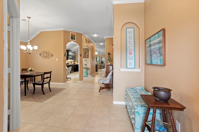 interior space with light tile patterned floors, baseboards, arched walkways, ornamental molding, and a chandelier