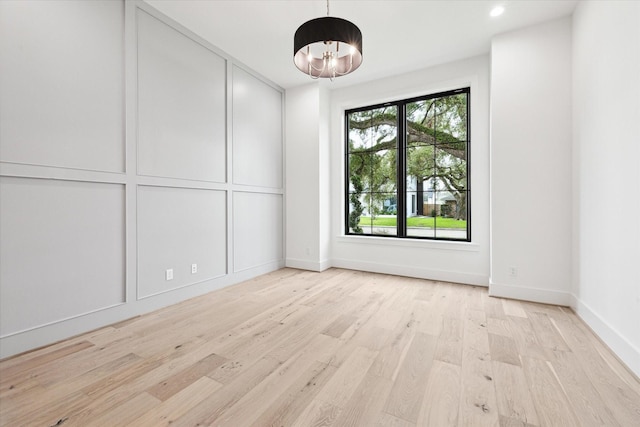 empty room featuring light wood-type flooring and an inviting chandelier