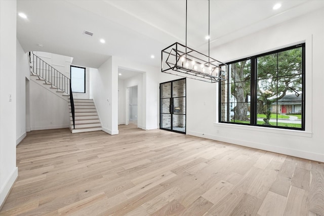 unfurnished dining area featuring a chandelier and light hardwood / wood-style flooring