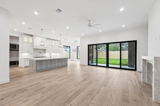 unfurnished living room with sink, ceiling fan, and light hardwood / wood-style flooring