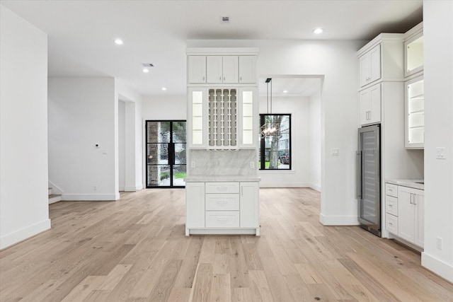 kitchen with white cabinetry, beverage cooler, and light wood-type flooring