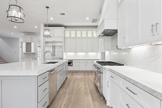 kitchen featuring hanging light fixtures, custom range hood, white cabinets, premium appliances, and a spacious island