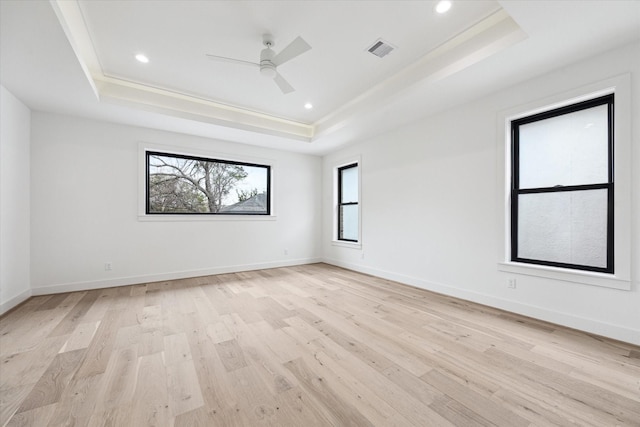 unfurnished room with ceiling fan, light hardwood / wood-style floors, and a raised ceiling