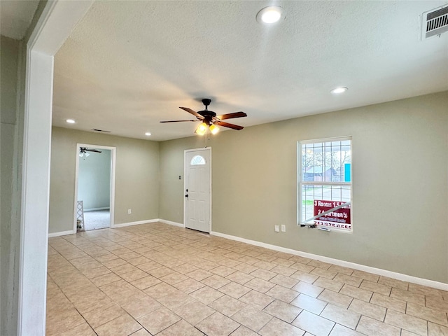 tiled entryway with a textured ceiling and ceiling fan