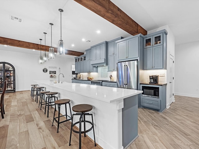 192 B Fm 1097, New Waverly, TX 77358 - kitchen featuring high quality appliances, beamed ceiling, light wood-style flooring, a sink, and a breakfast bar area