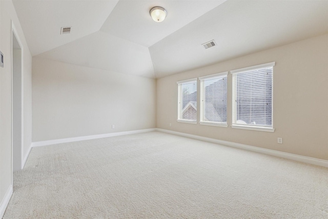 carpeted spare room featuring vaulted ceiling