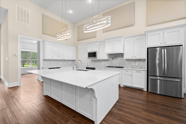 kitchen featuring appliances with stainless steel finishes, hanging light fixtures, and white cabinets