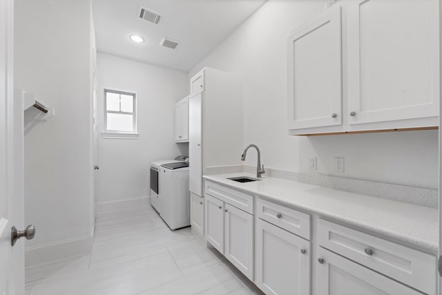 laundry area featuring cabinets, washing machine and dryer, and sink