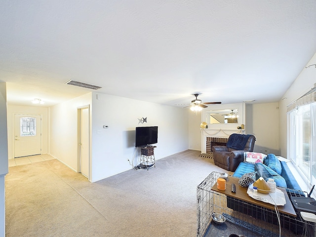 living room with light carpet, a wealth of natural light, a brick fireplace, and visible vents