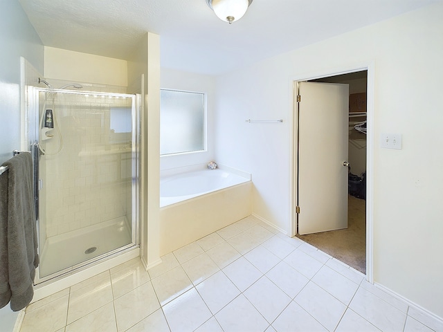 bathroom featuring a stall shower, tile patterned flooring, a walk in closet, and a bath