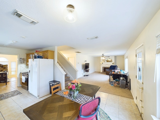 dining room featuring light carpet, a brick fireplace, light tile patterned floors, and visible vents