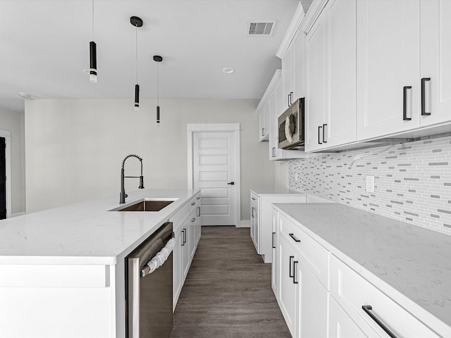 kitchen with pendant lighting, sink, appliances with stainless steel finishes, an island with sink, and white cabinets