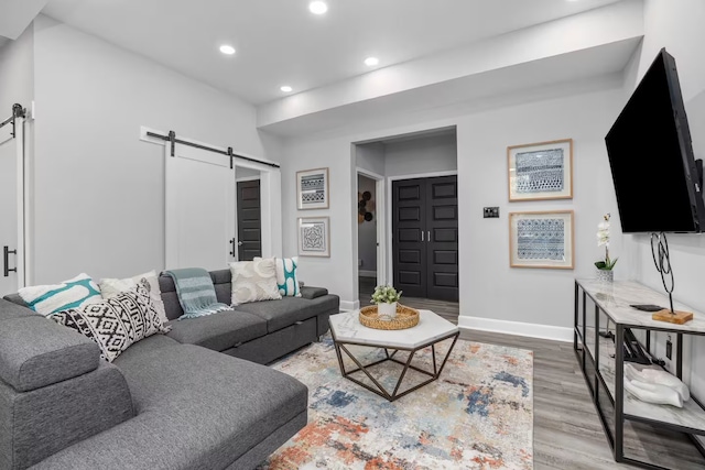 living room with a barn door and light hardwood / wood-style floors