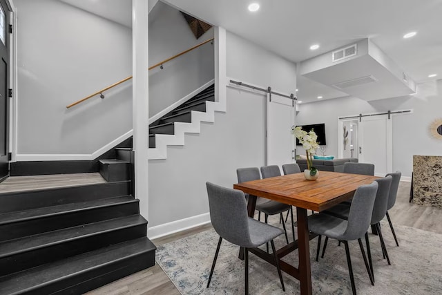 dining space with hardwood / wood-style flooring and a barn door