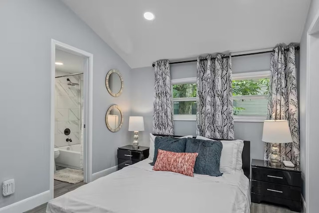 bedroom featuring hardwood / wood-style flooring, ensuite bath, and lofted ceiling