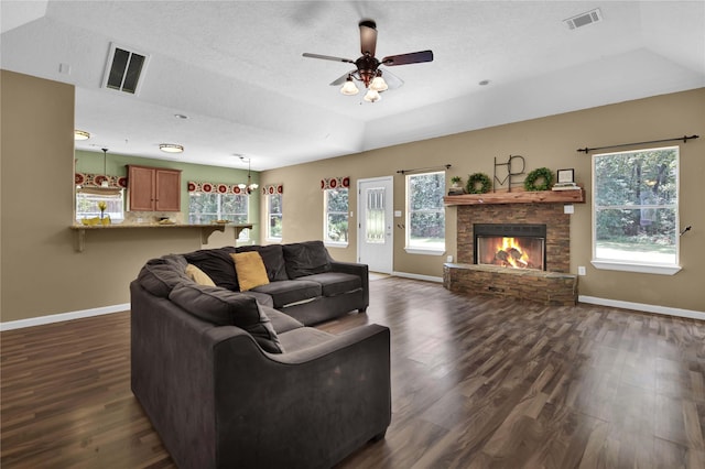 living room featuring vaulted ceiling, dark hardwood / wood-style floors, a fireplace, ceiling fan, and a textured ceiling