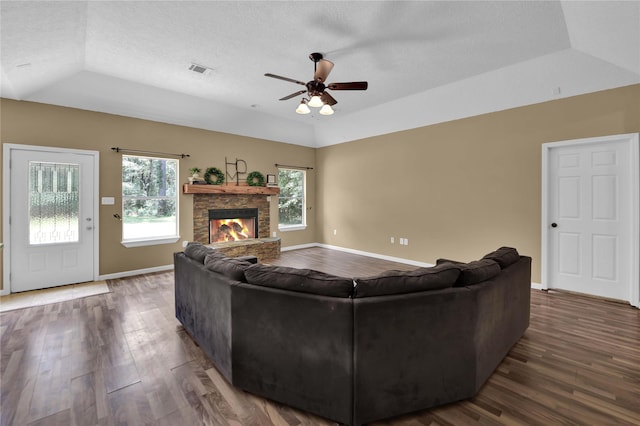 living room with a stone fireplace, a textured ceiling, lofted ceiling, and dark hardwood / wood-style flooring