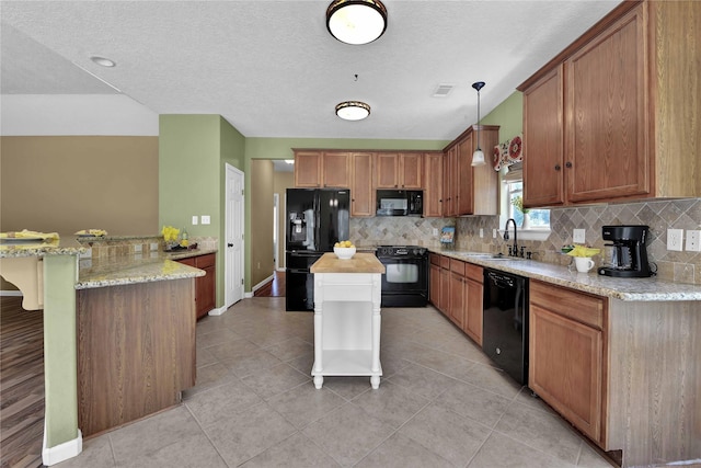 kitchen with pendant lighting, black appliances, sink, light stone counters, and kitchen peninsula